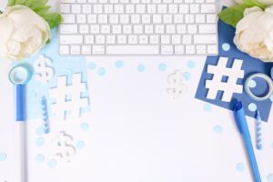 white desk with light blue and dark blue props like a keyboard, white flowers, markers, confetti, a notebook