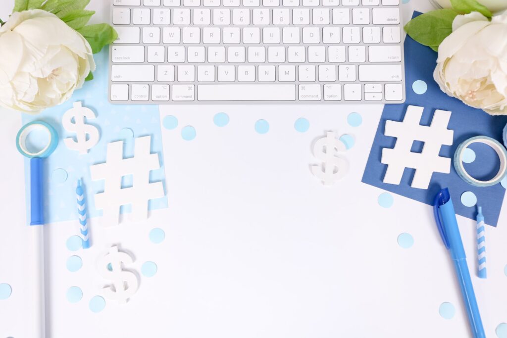 white desk with light blue and dark blue props like a keyboard, white flowers, markers, confetti, a notebook