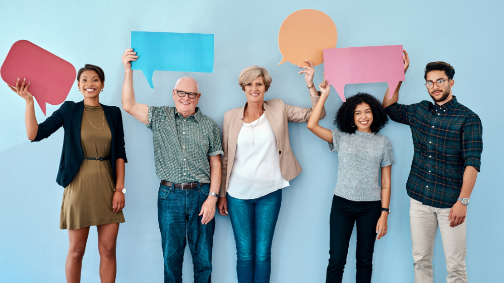Diverse group of business people holding up speech bubbles against blue background